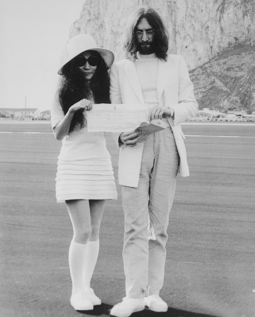 24 Mar 1969, Gibraltar --- Original caption: Beatle John Lennon and his bride, Japanese-born Yoko Ono, hold the marriage certificate following their registry office wedding here on March 21st. Providing the background in the picture is the famous Rock of Gibraltar. This was Lennon's second marriage and 34-year-old Yoko's third. --- Image by © Bettmann/CORBIS